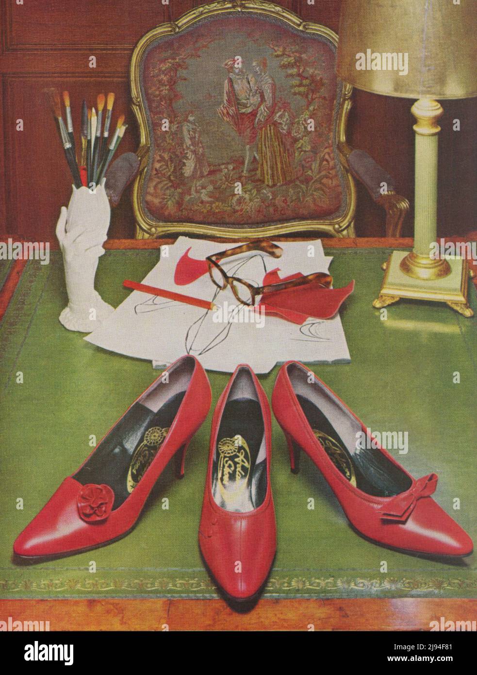 Photograph three red shoes on the desk glasses brushes vintage paper age of a magazine 1980s 19702 Stock Photo