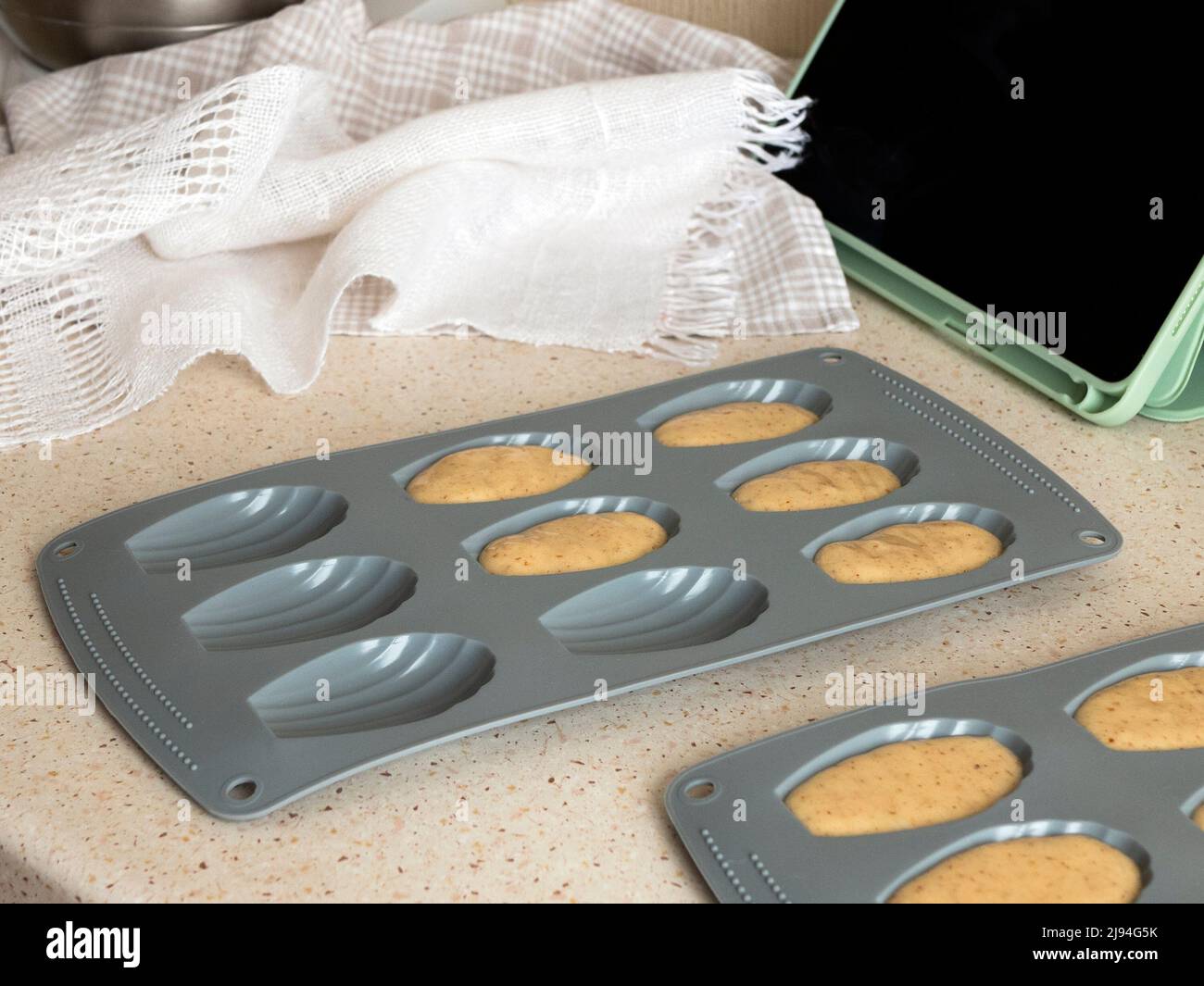 Filling batter in madeleine pan, selective focus. Making madeleine cookies, online cooking class