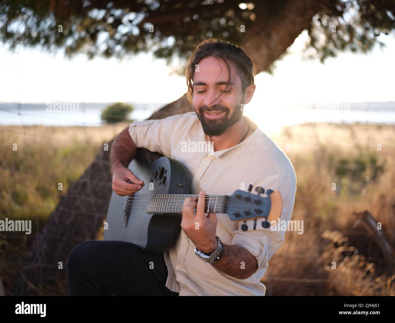 Male guitarist with one knee on the ground playing the guitar with his
