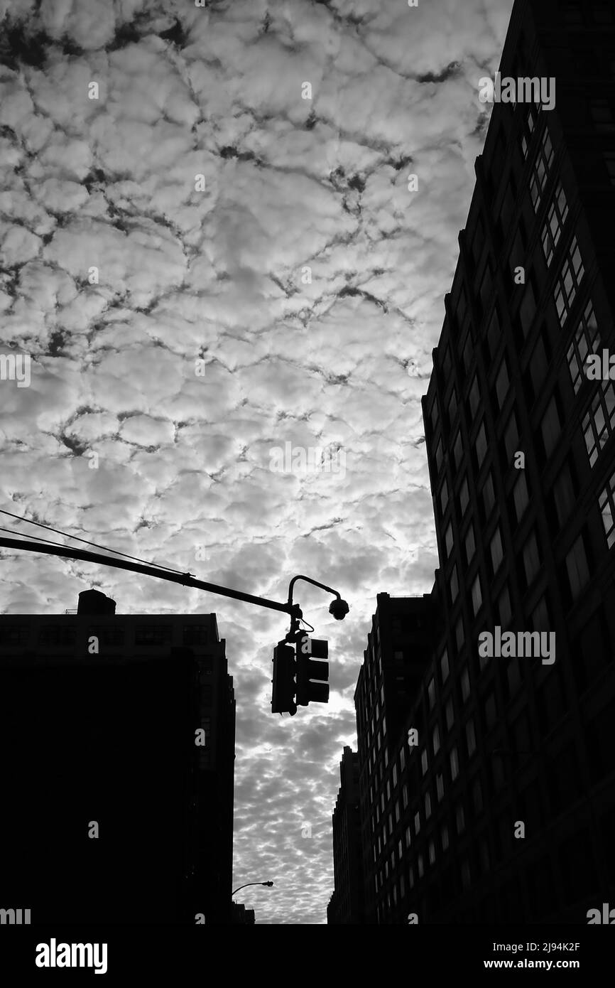Clouds and buildings in black and white looking up from the street Stock Photo