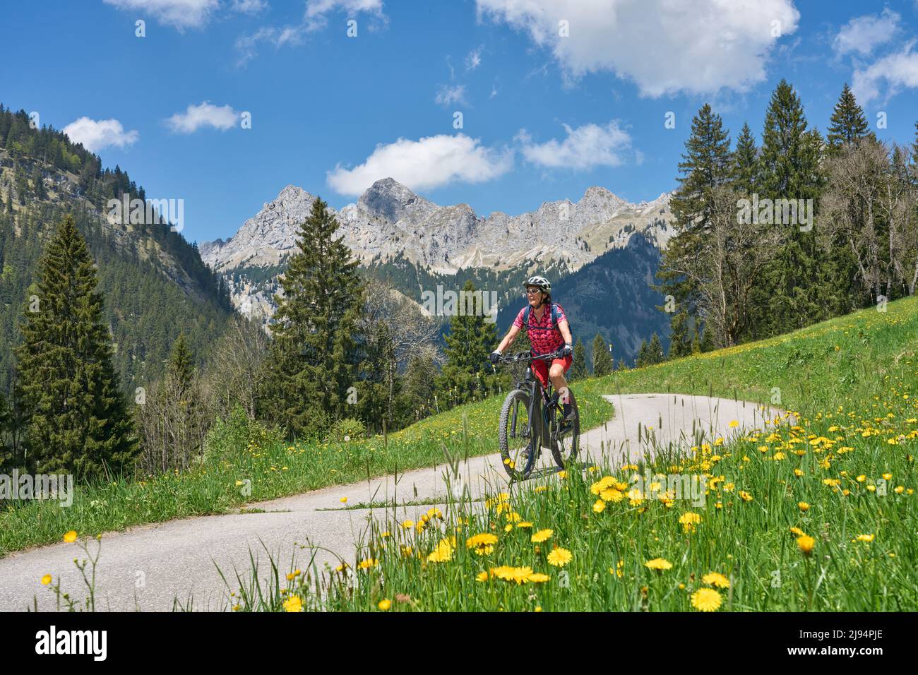 nice senior woman riding her electric mountain bike on the old Gaicht Pass road from Lech Valley up to the Tannheim Valley in Tyrol, Austria Stock Photo
