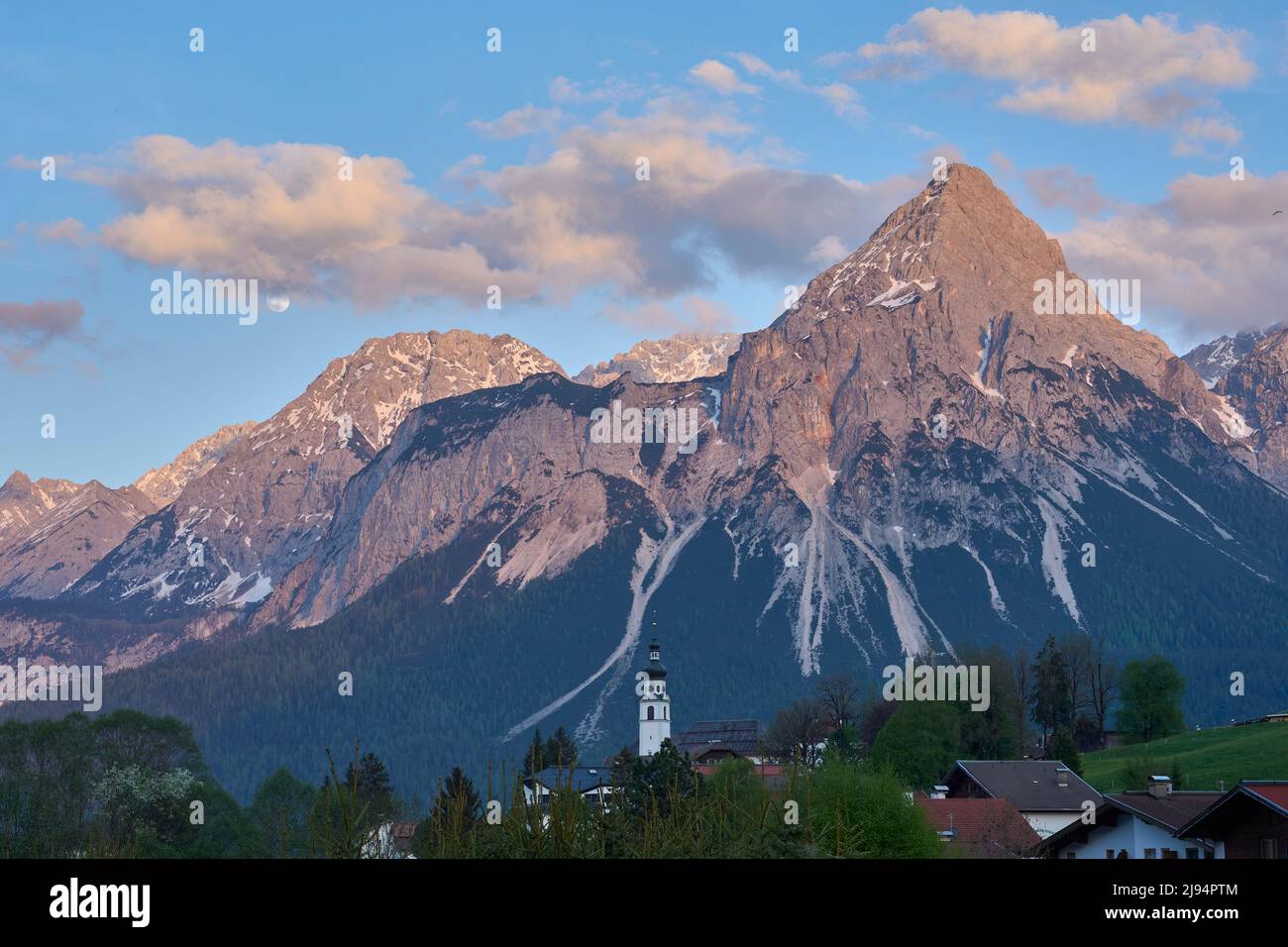 Full moon rises over the steep summits of Wetterstein mountain range high above Ehrwald in Tirol Austria, Landscape Stock Photo