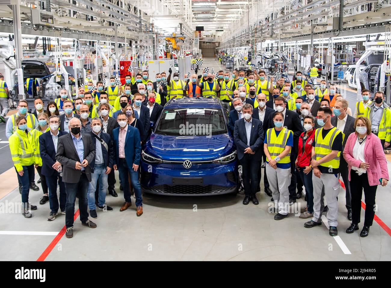Emden, Germany. 20th May, 2022. VW employees stand next to one of the first ID.4s produced in the new production hall. Volkswagen has started series production of the all-electric ID.4 compact SUV at its plant in Emden, East Frisia. After the ramp-up phase, 4000 e-vehicles per week are to be produced in Emden by the end of the year. Credit: Sina Schuldt/dpa/Alamy Live News Stock Photo