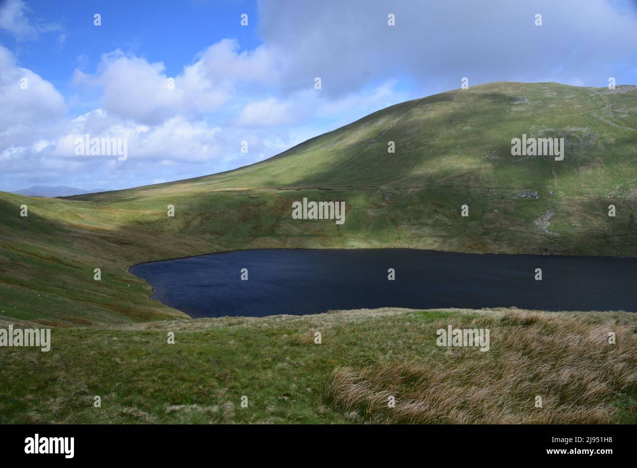 Glacial Grisedale Tarn nestles in the surrounding high level hills in