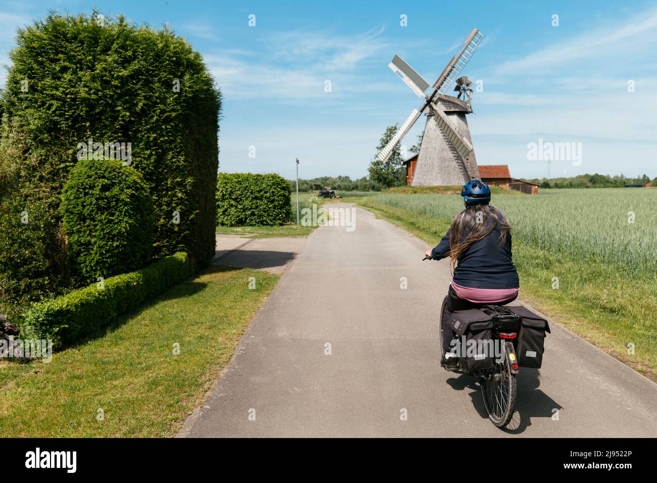 Woman on an e-bike cycling towards the smock mill from 1802 in Petershagen-Bierde Stock Photo