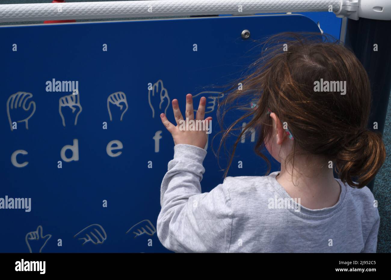 A young girl looks over a sign language chart in a playground in Edmonton, Alberta, Canada Stock Photo