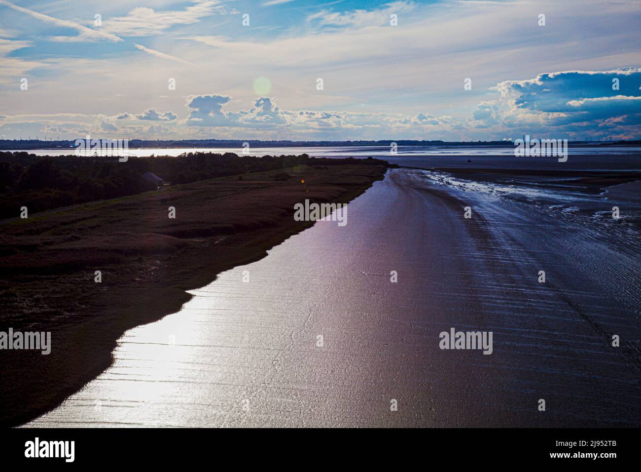 edge of land with vividly lit up mud dunes with Humber Estuary, UK captured from the Humber Bridge Stock Photo