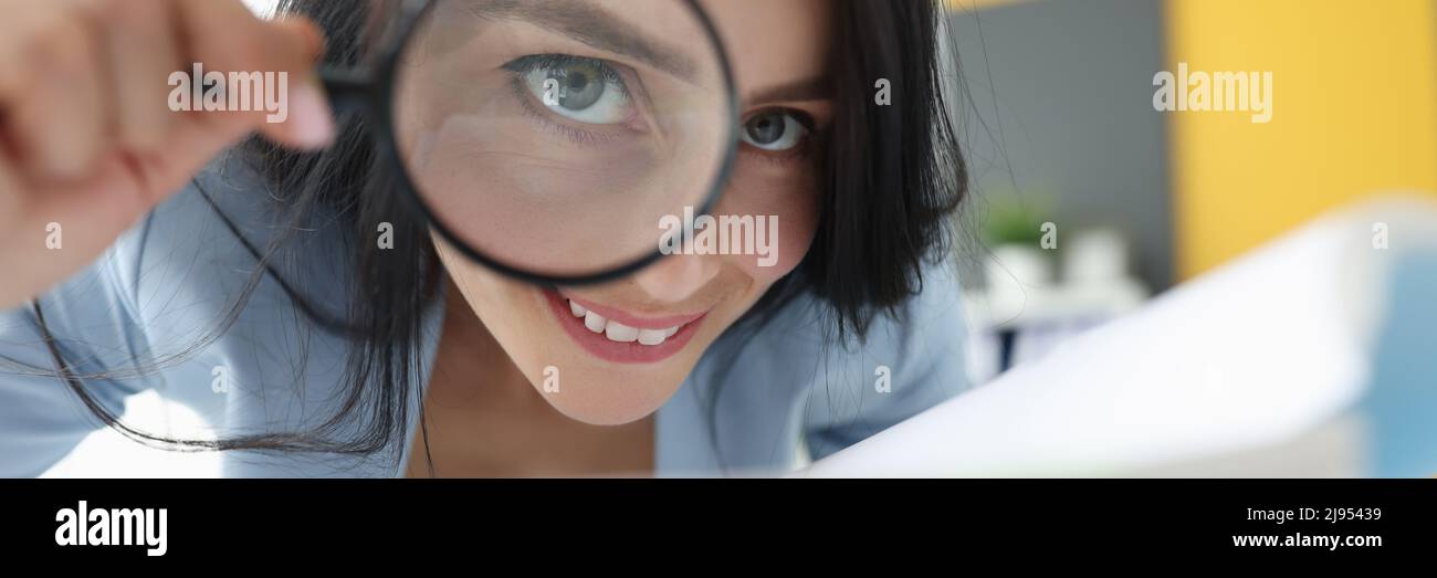 Joyful woman looking through a magnifying glass Stock Photo - Alamy