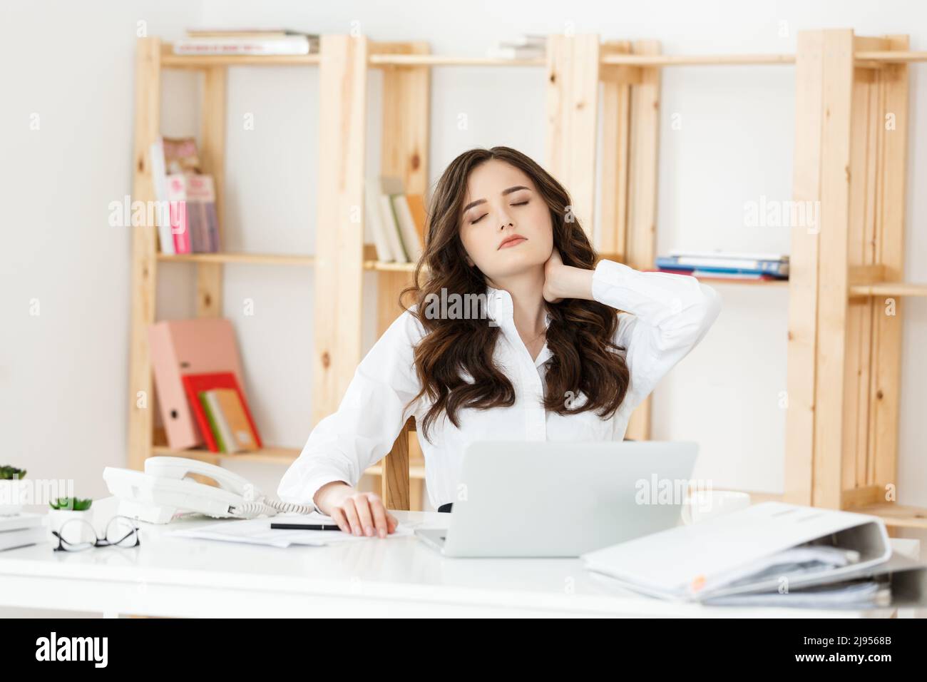 Tired young businesswoman suffering from long time sitting at computer ...