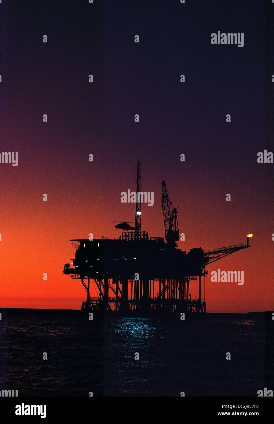 Australia. Industry. Bass strait. Helicopter landing on Southern Cross oil rig at sunset. Stock Photo