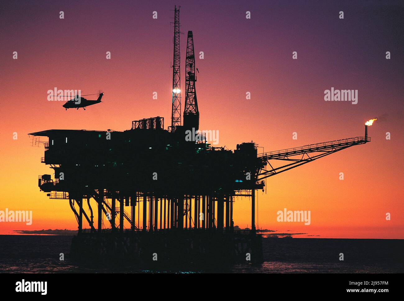 Australia. Industry. Bass Strait. Helicopter landing on Southern Cross oil rig at sunset. Stock Photo