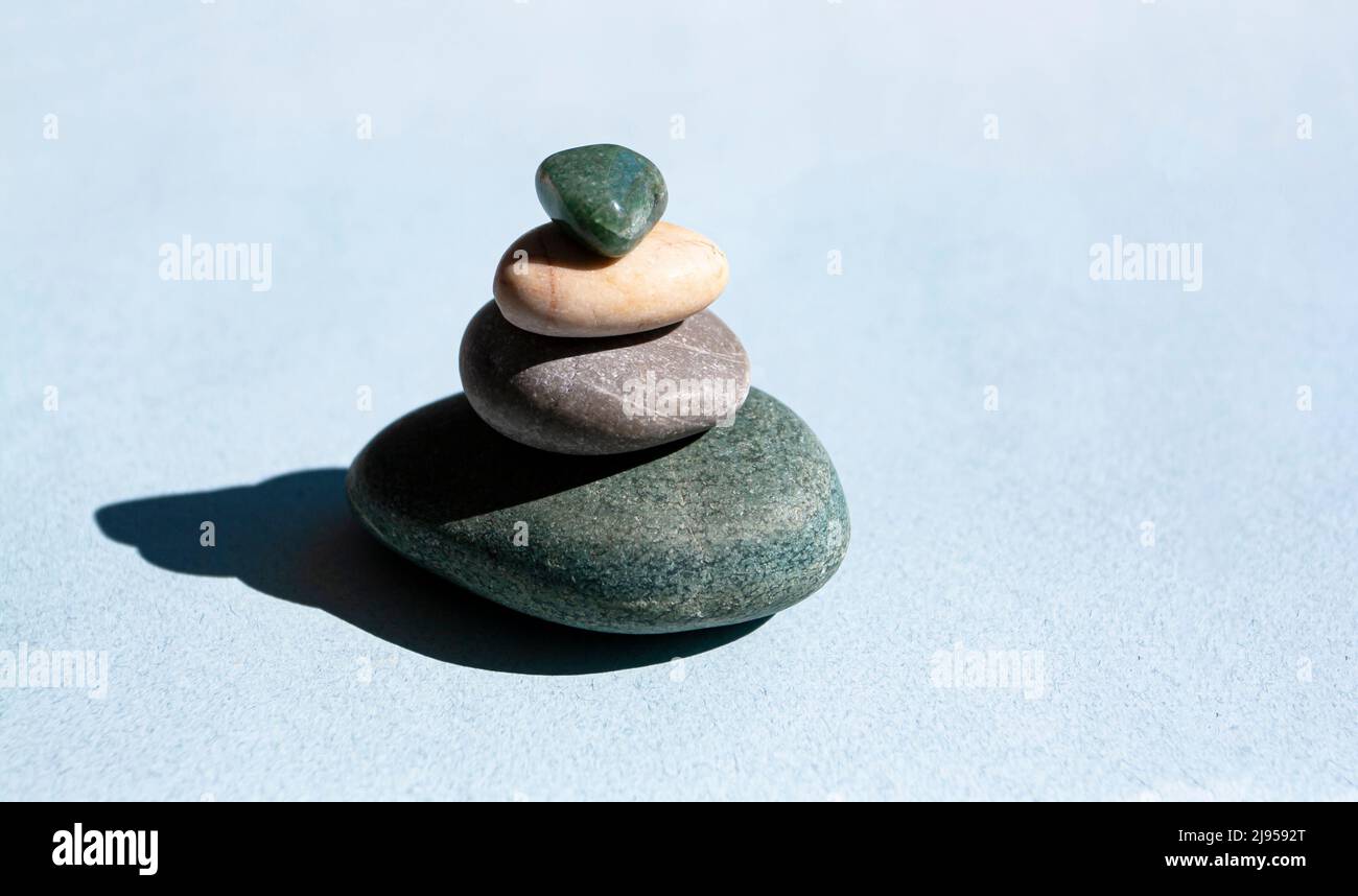 Stone mountain on a blue background, a tower of four stones, simple balanced stones, simplicity, harmony and balance. Minimalist concept. Stock Photo