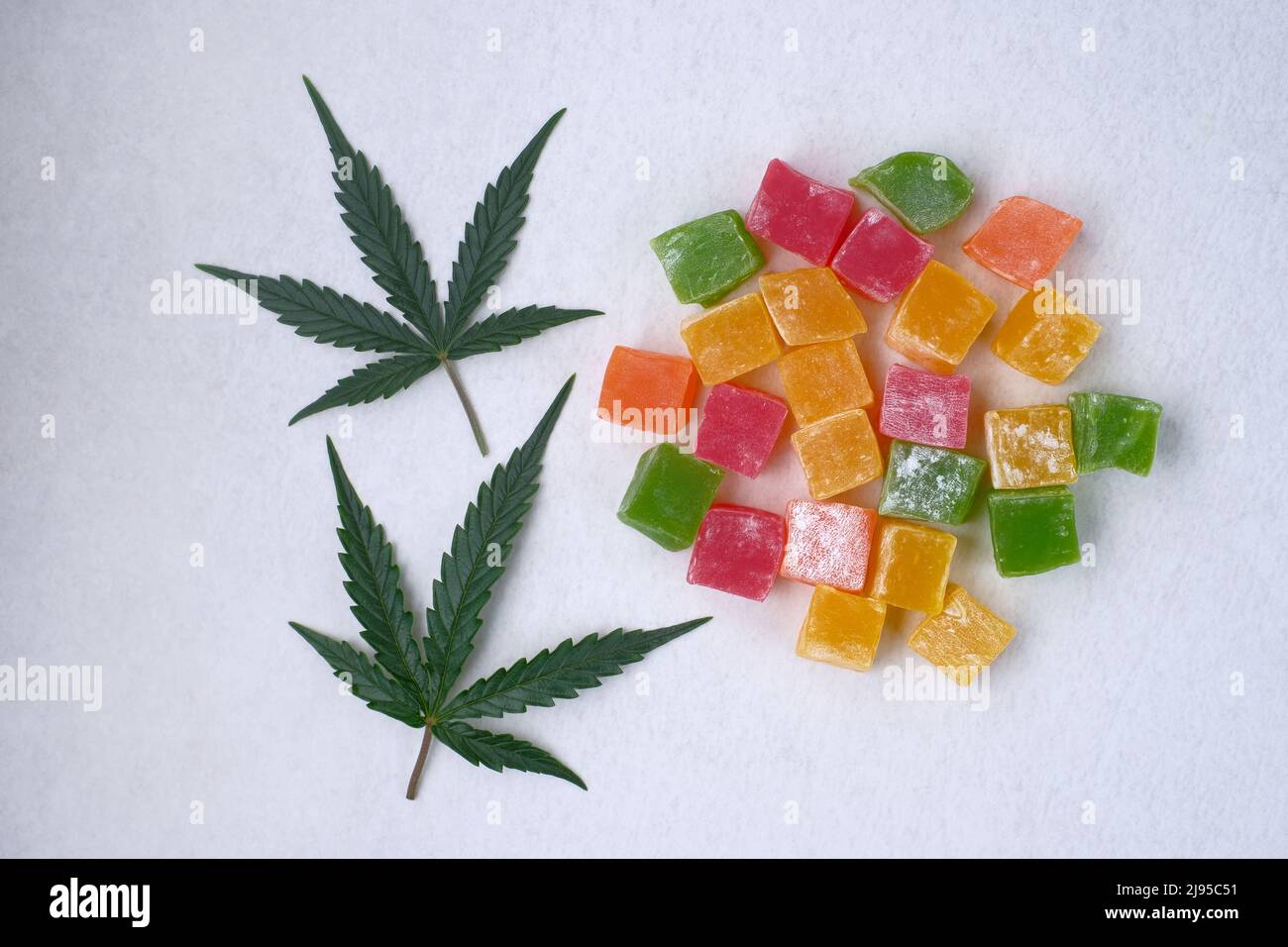 Layout of colorful marmalade and marijuana leaf on white textured