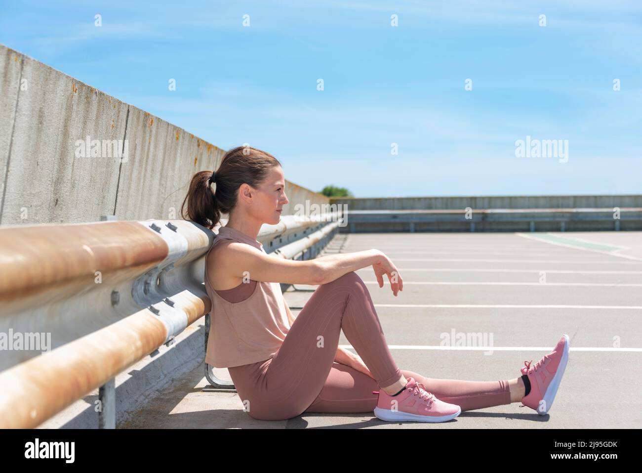 Fit sporty woman sitting, resting after working out outside Stock Photo