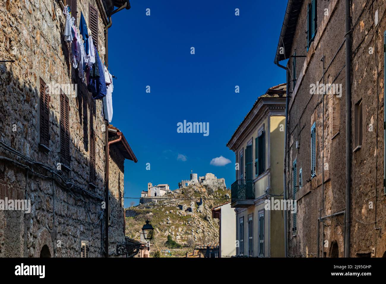 The small village of Tolfa, in Lazio. The view of the fortress and the church of the Sanctuary at the top of the cliff. A glimpse of the town with its Stock Photo