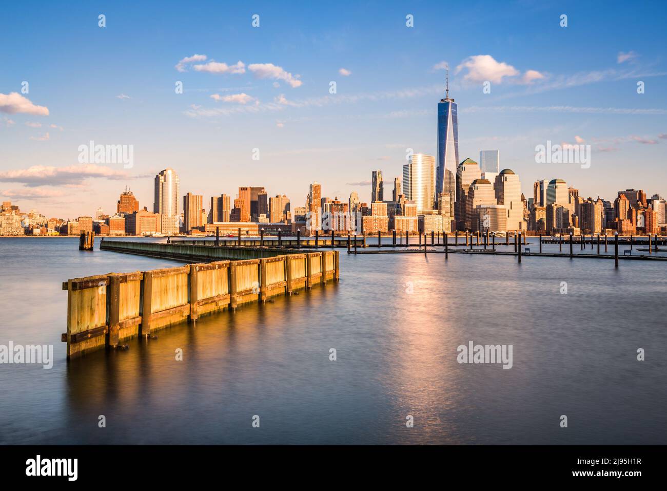 Downtown New York as observed from Jersey City, across the Hudson River. The Financial District skyscrapers have an orange glow under a bright sunset Stock Photo