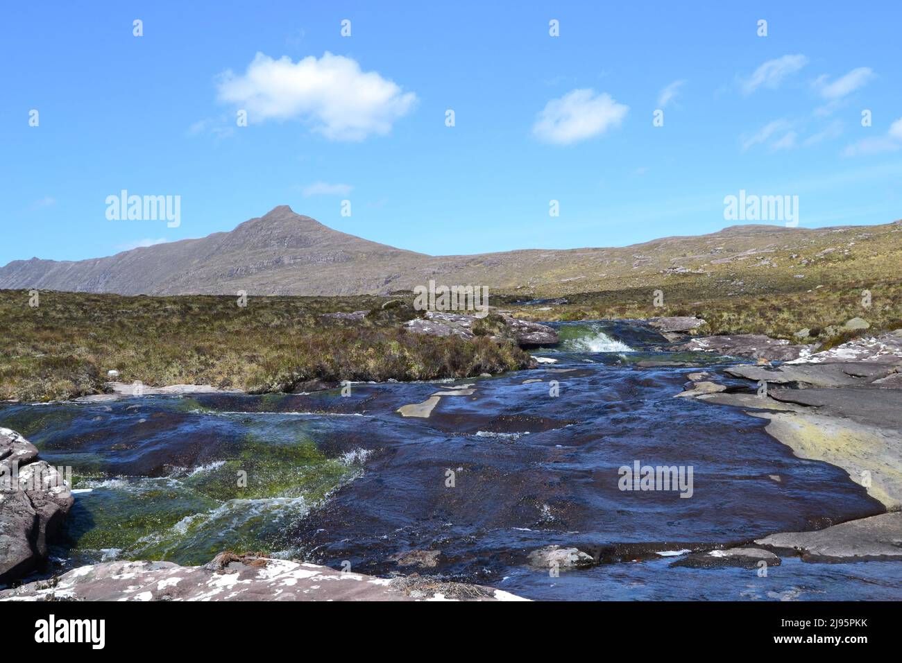 Fast flowing rivers near Ben Mor Coigach, a high ridge near Ullapool in Ross & Cromarty/Assynt in NW Scotland with gorse in flower on a bright spring Stock Photo