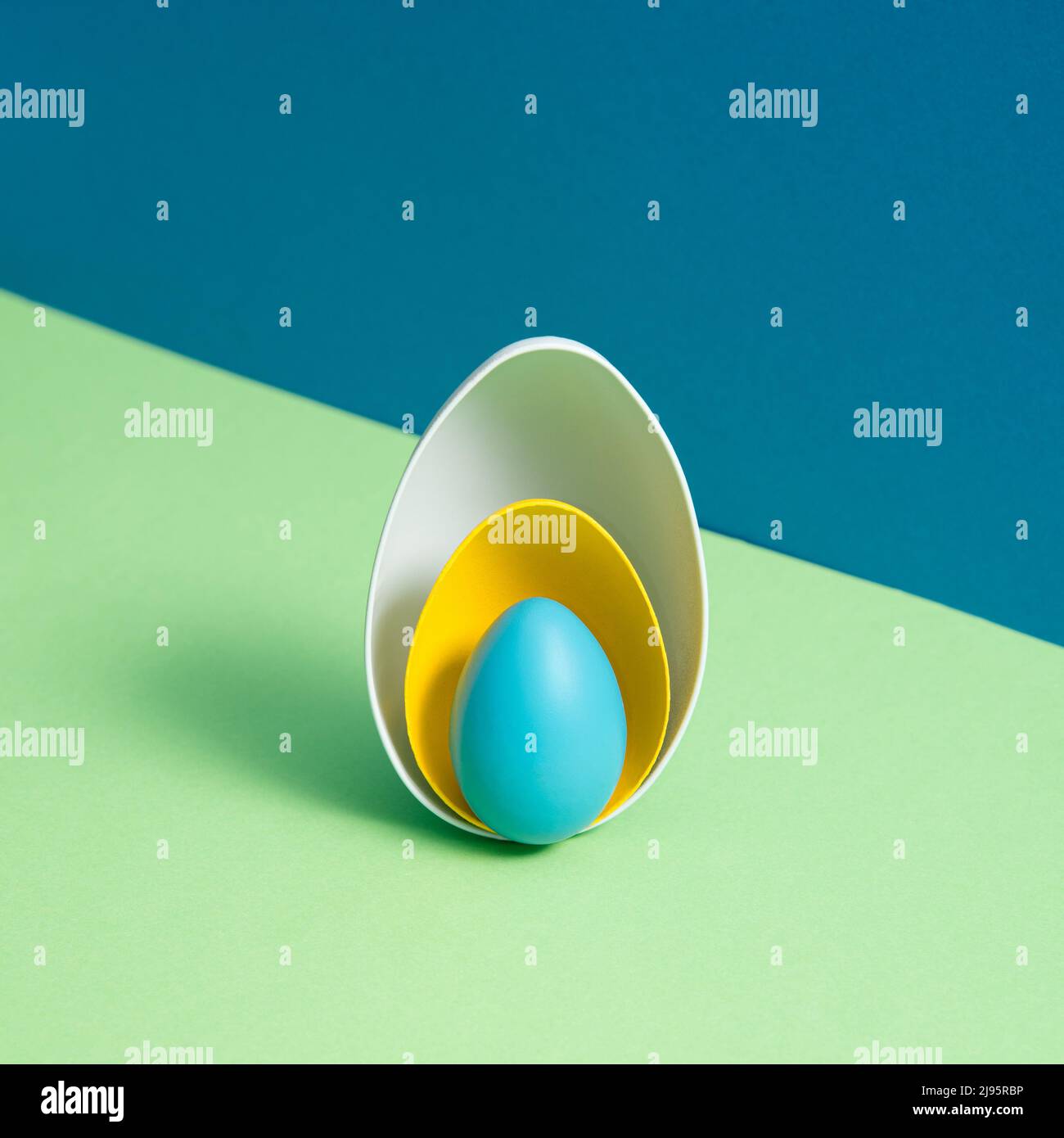 White and yellow eggshells and the whole blue egg on blue and green background. Minimal Easter holiday concept. Creative copy space. Isometric layout Stock Photo