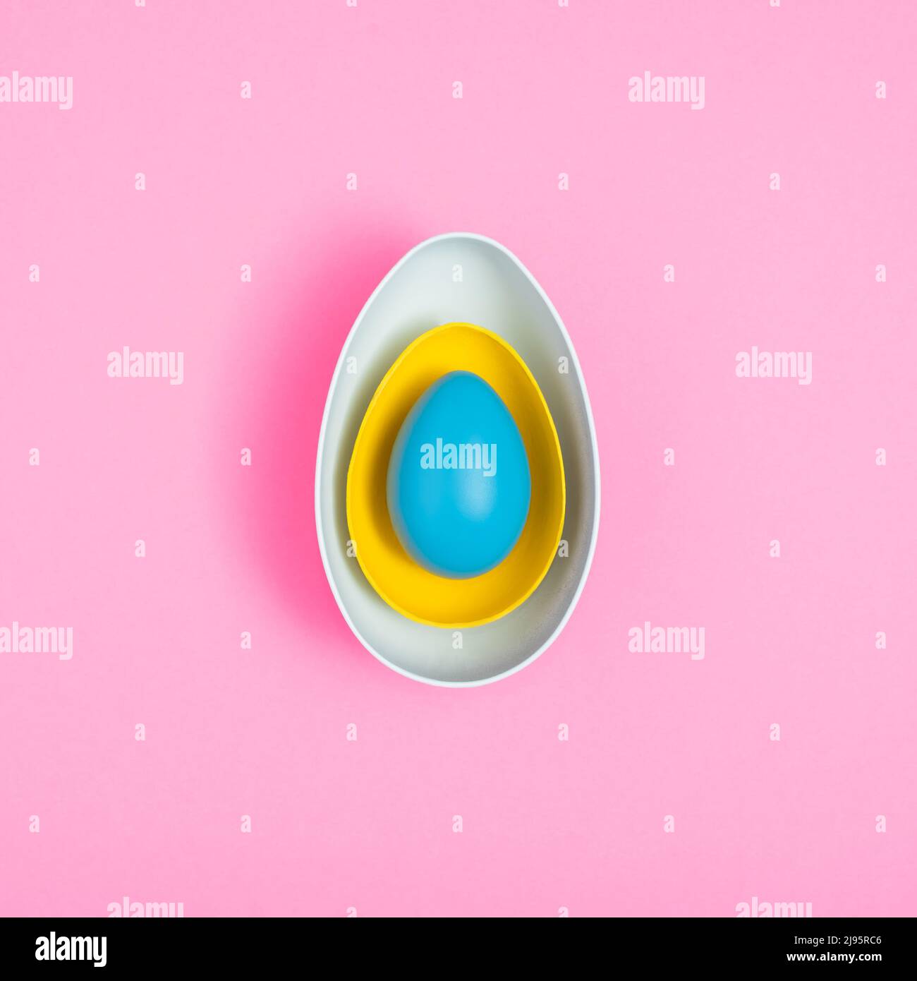 White and yellow eggshells and the whole blue egg isolated on a pink background. Minimal Easter holiday concept. Creative copy space. Top view. Stock Photo