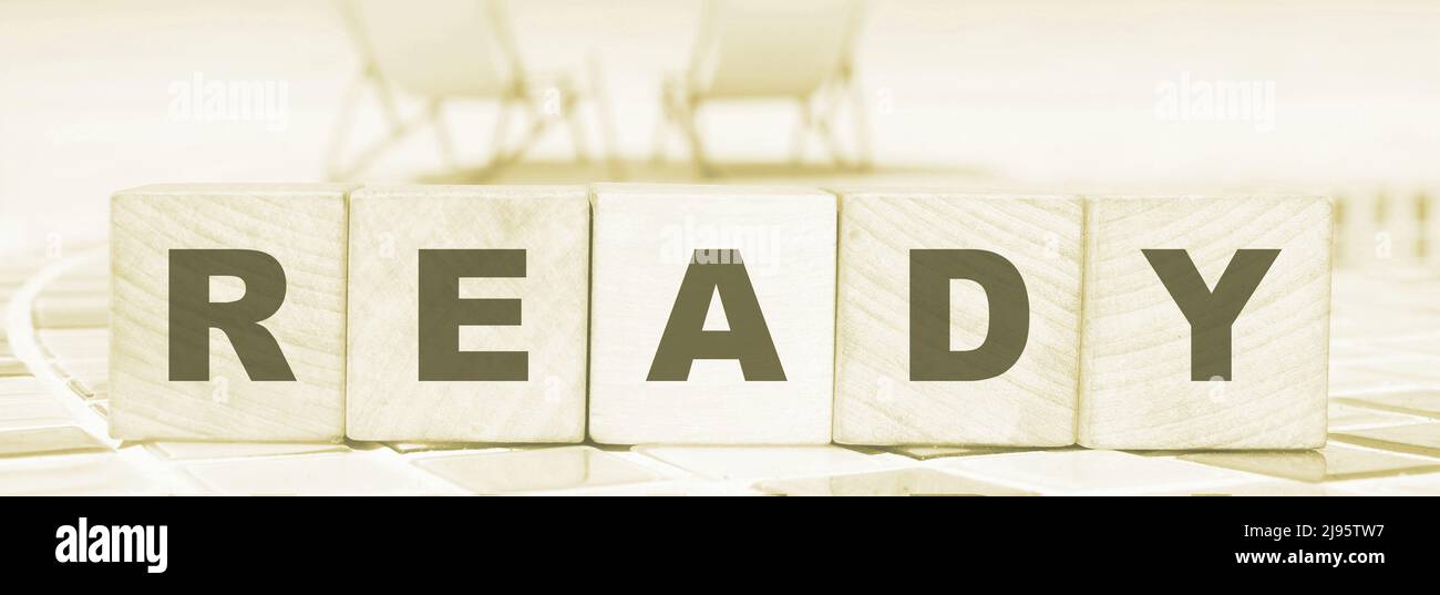 word ready made with wooden blocks standing on swimming pool border ...