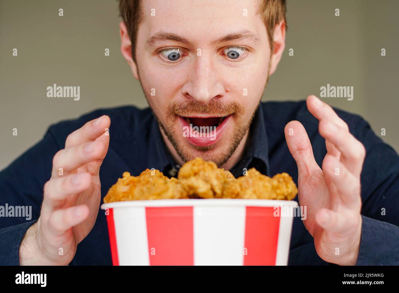 Hungry excited man looking at busket with fried chicken wings. Stock Photo