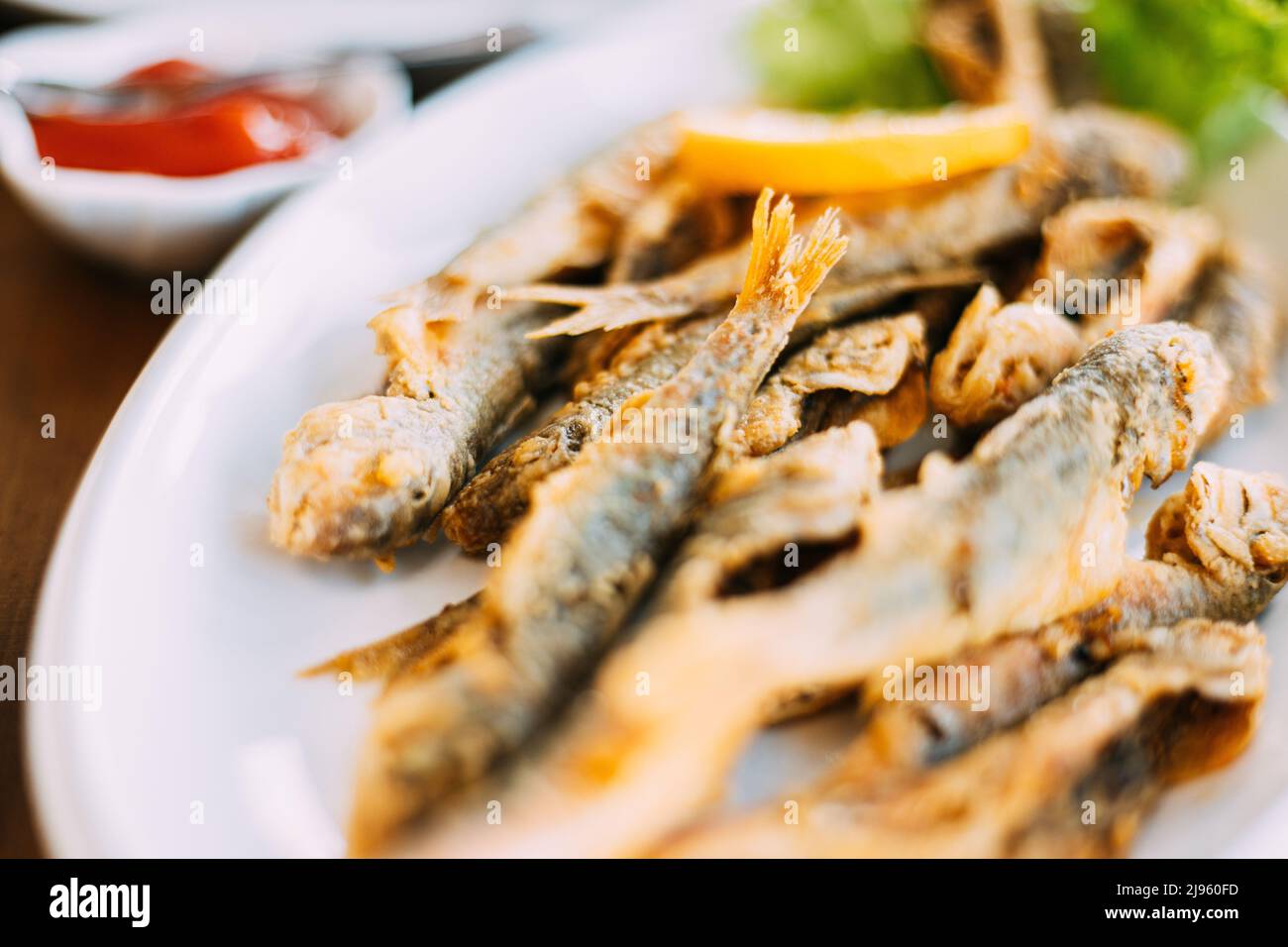 Dish with Mullet Fish With orange. Fried fry small fishes Stock Photo