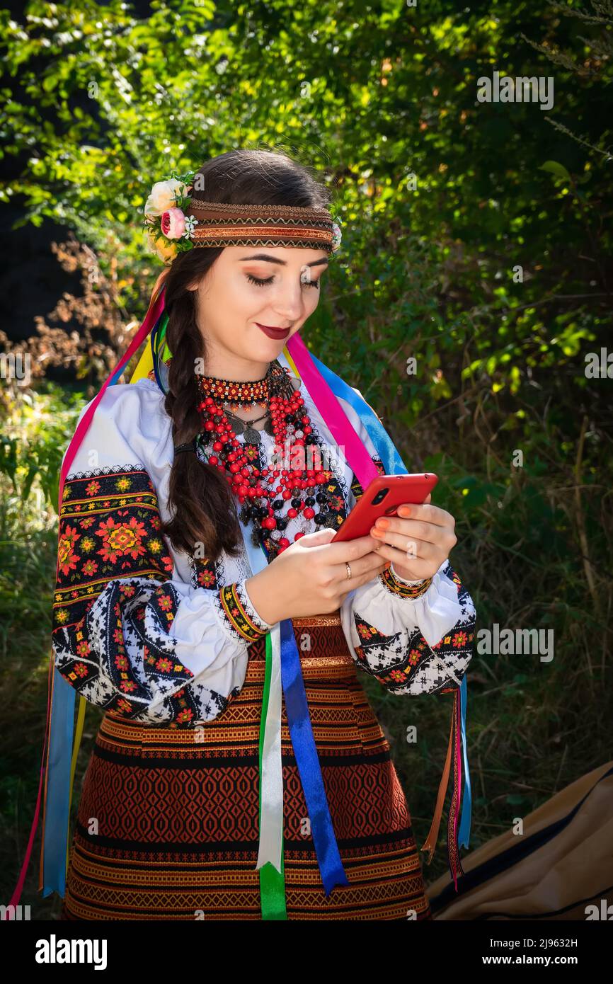 Ukrainian woman in an embroidered shirt holds a mobile phone in her hands. Stock Photo