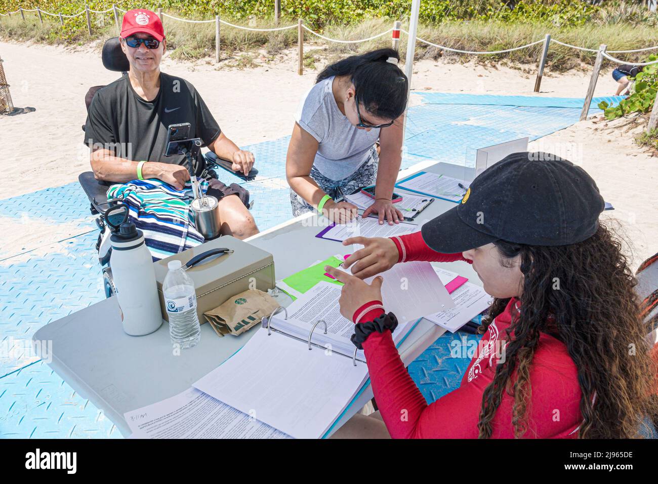Miami Beach Florida,Sabrina Cohen Adaptive Beach Day,disabled special needs handicapped WaterWheels floating wheelchair,man registering Stock Photo