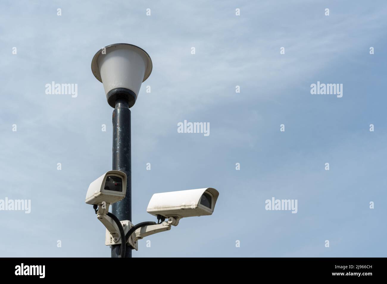 Surveillance cameras mounted on a lamp post against a blue sky. security cctv camera. Security in the city. Hidden filming of what is happening. Moder Stock Photo