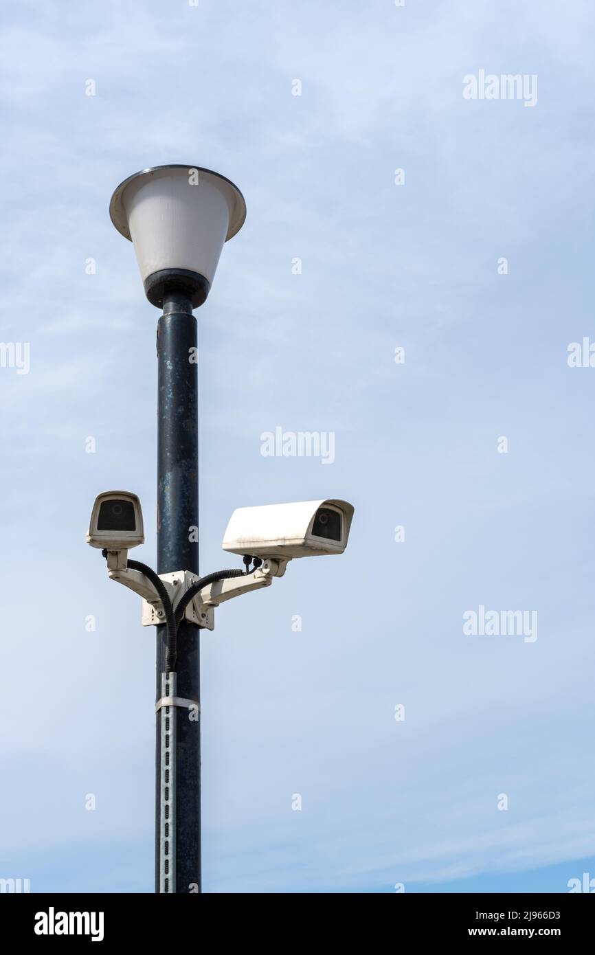 Surveillance cameras mounted on a lamp post against a blue sky. security cctv camera. Security in the city. Hidden filming of what is happening. Verti Stock Photo