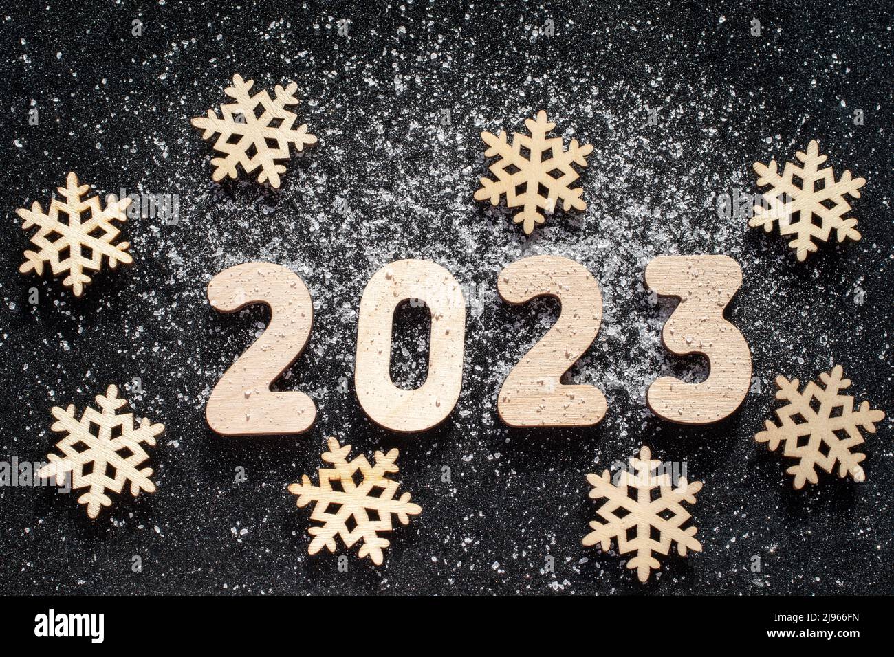 New Years concept Wooden snowflakes and numbers 2023 sprinkled with