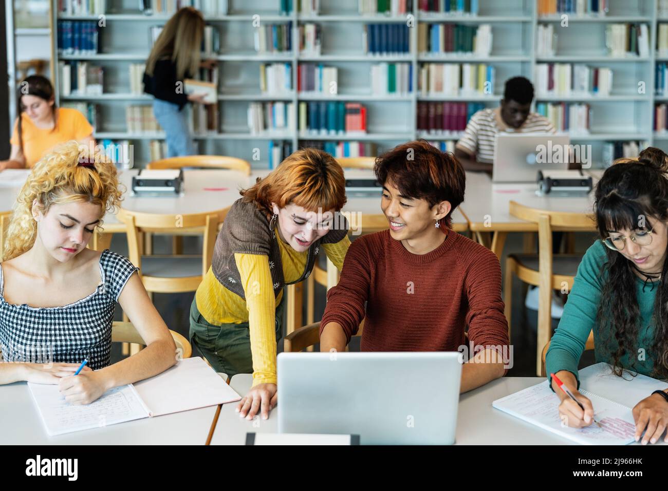 Young university students using laptop and studying with books in