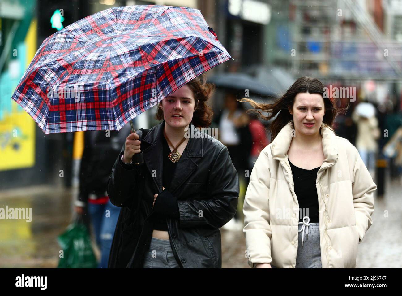 A woman tries to hold onto her umbrella as the downpour hits Manchester ...