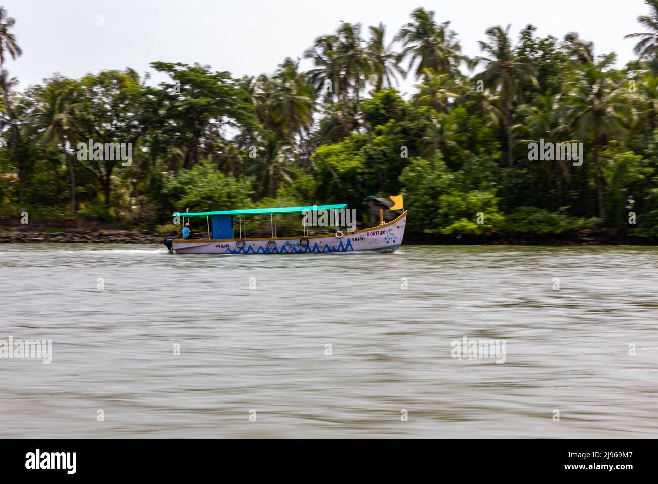 Panning shot of motor boat carrying tourists on Karli River in Devbag, Malvan, Maharashtra Stock Photo