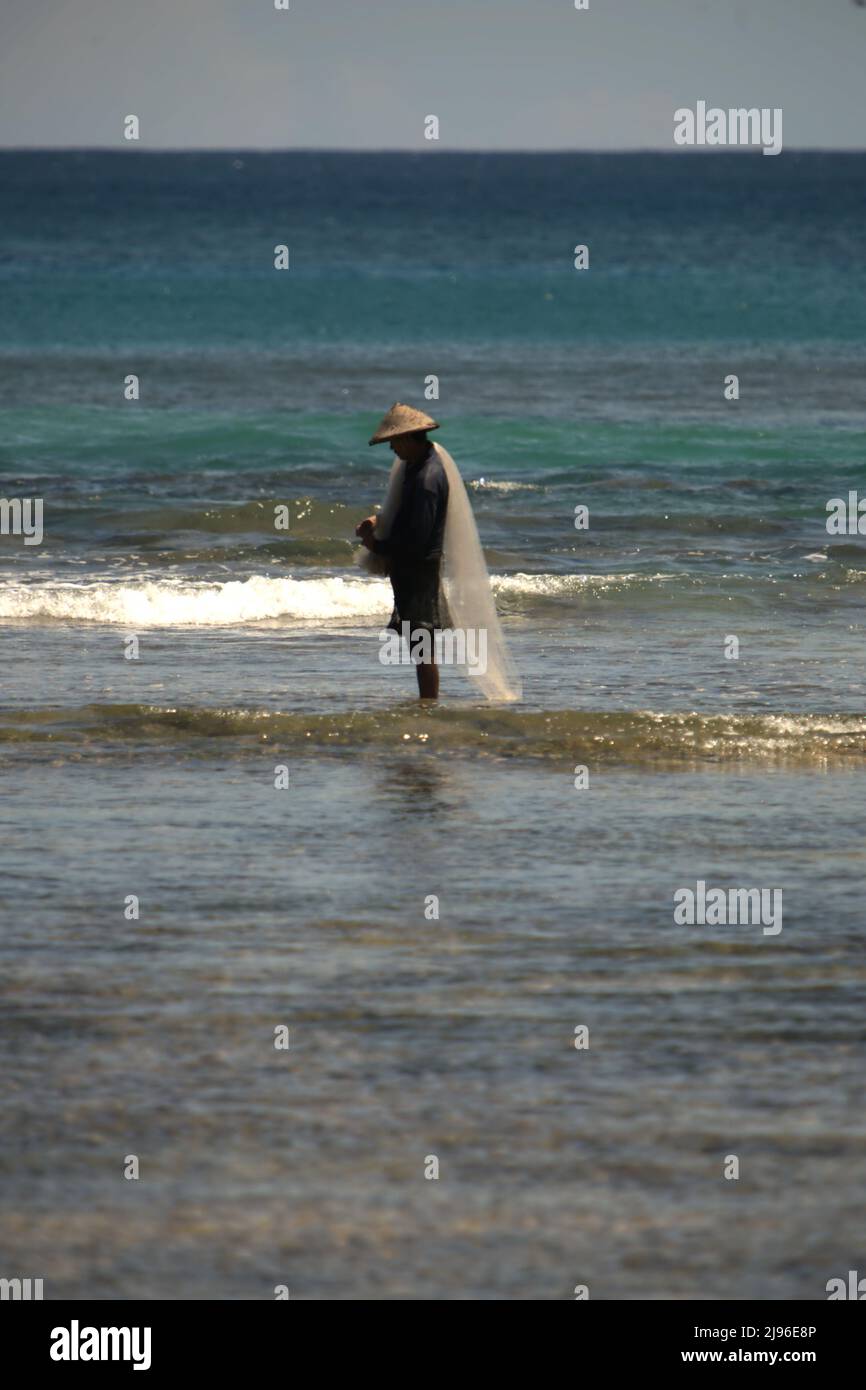 A fisherman preparing fishing net to fish on the coastal water of Tanjung Setia beach in Krui, Pesisir Barat, Lampung, Indonesia. Stock Photo