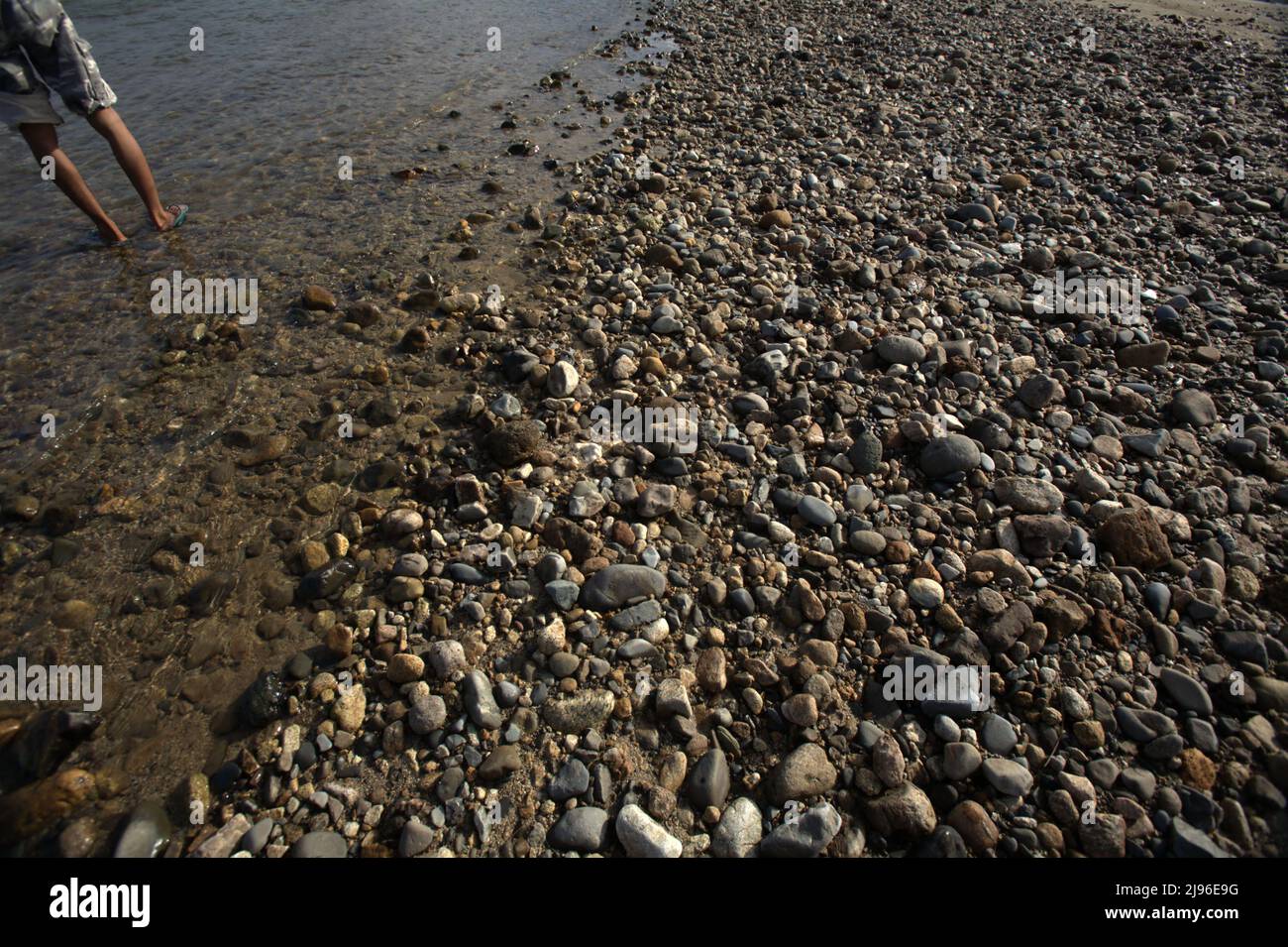 A man standing on a riverbed near Lubuk Sikaping, Pasaman, West Sumatra, Indonesia. Stock Photo