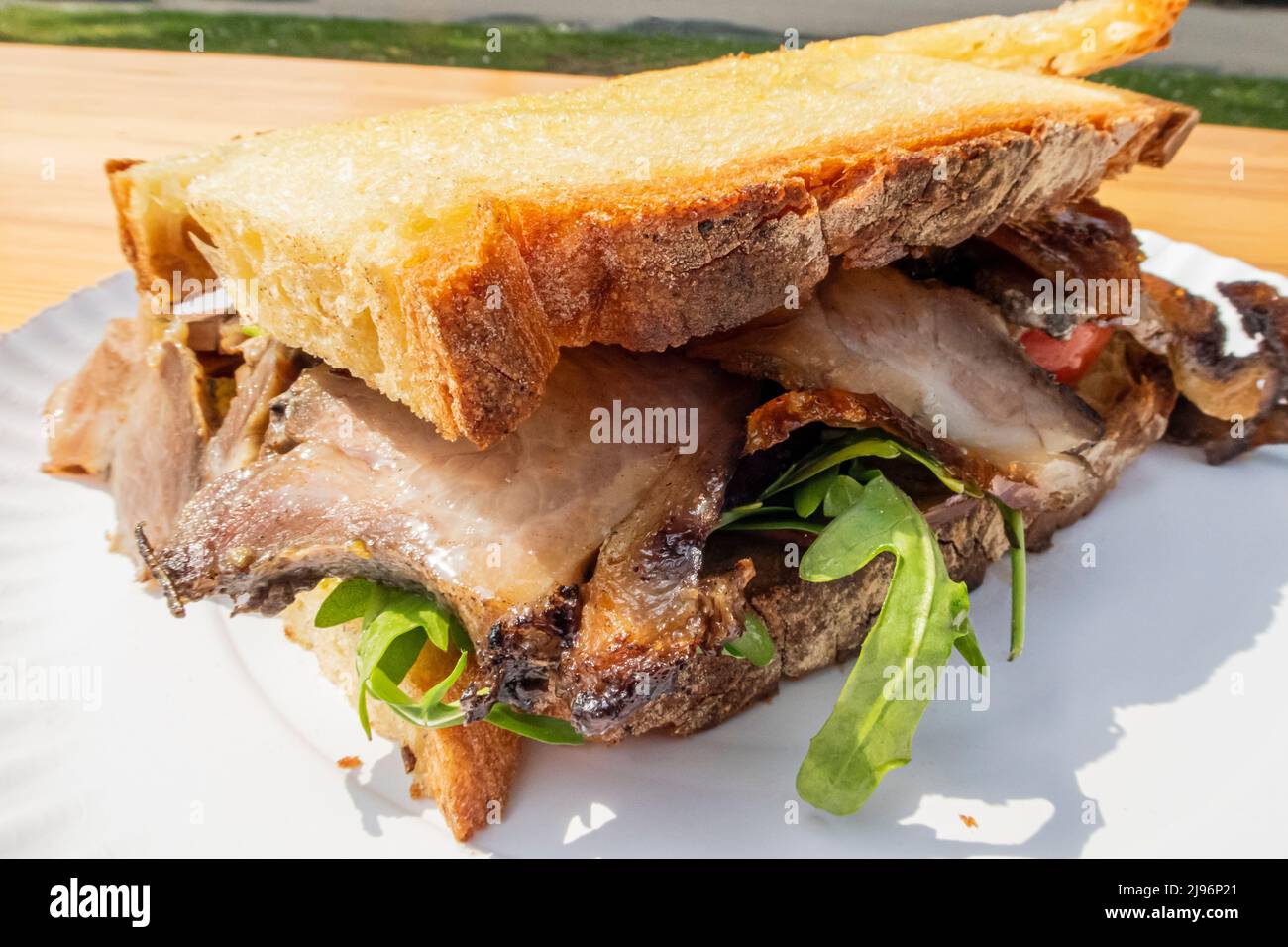 Farmer's bread sandwiched with suckling pig and rucula, close-up Stock Photo