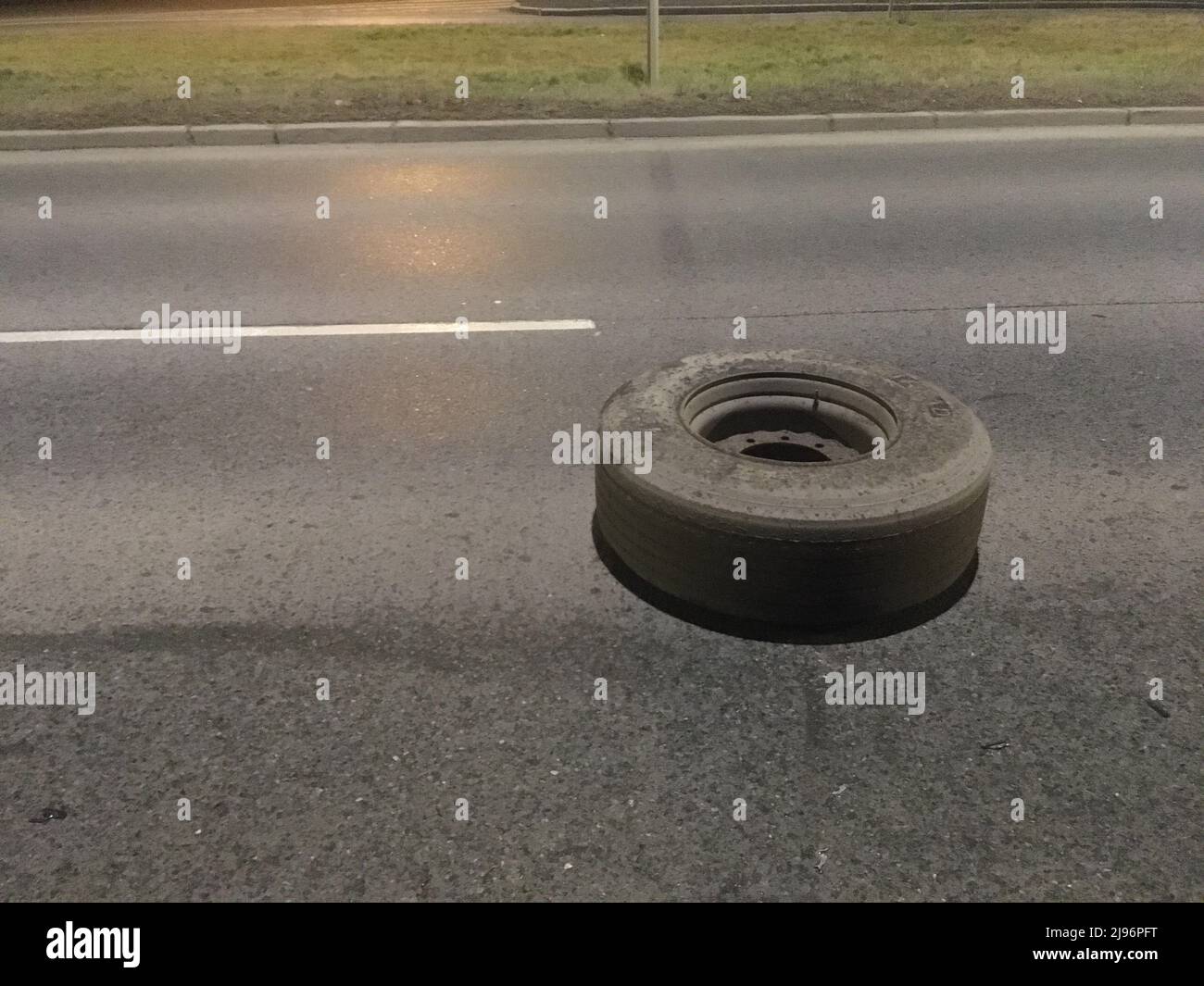 The dangerous obstacle lying on the road, the fallen of wheel from the truck. Accident can easily happen. Stock Photo