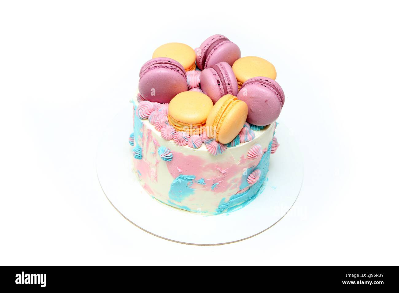 The small colorful and delicious cake with several macrons on it. Isolated on a white background. Stock Photo