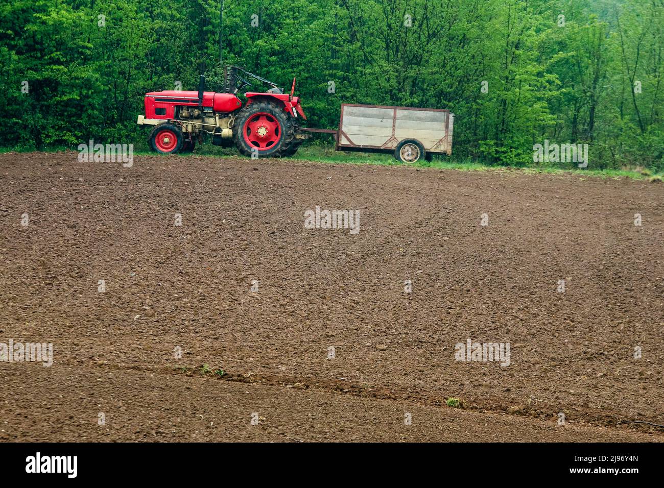 The old, veteran but reliable tractor standing on the field. Symbol for rural agriculture and machinery used there. Stock Photo