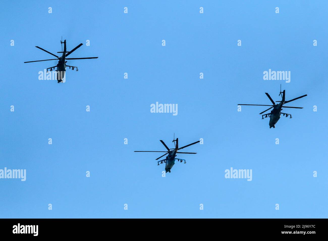 The flight of three soviet battle helicopters, type MIL Mi-24 flying on the bright blue sky. Stock Photo