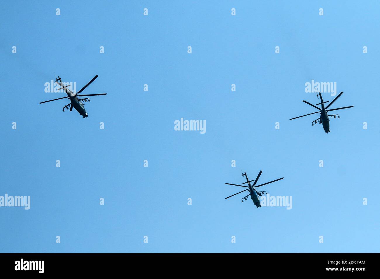 The flight of three soviet battle helicopters, type MIL Mi-24 flying on the bright blue sky. Stock Photo