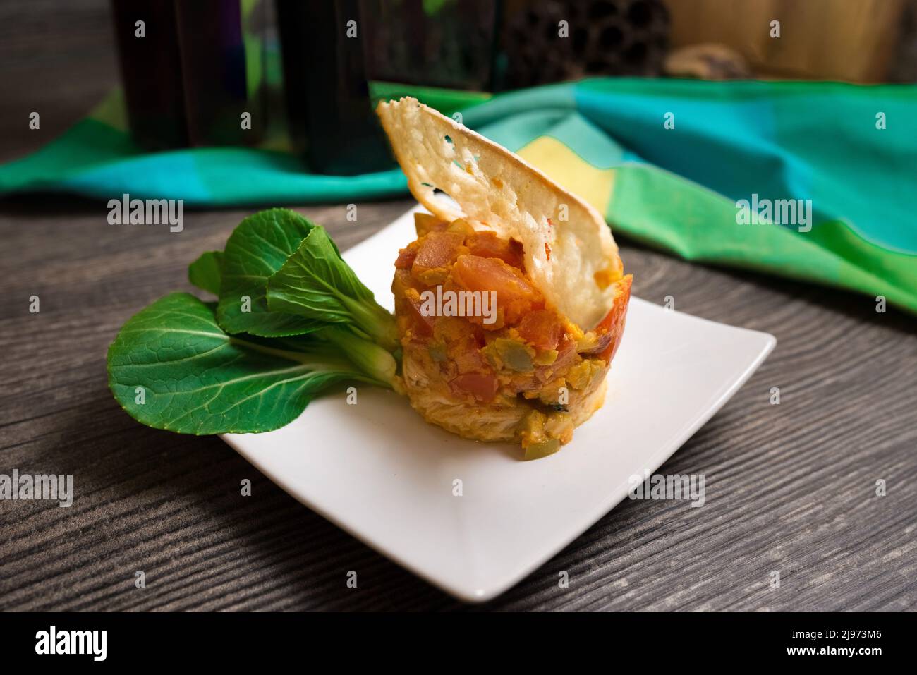 Chicken escalope with spicy tomato and olive relish. Decorated with slim slice of crouton, fresh young pak choi. Salad ring used to form a dish. Stock Photo