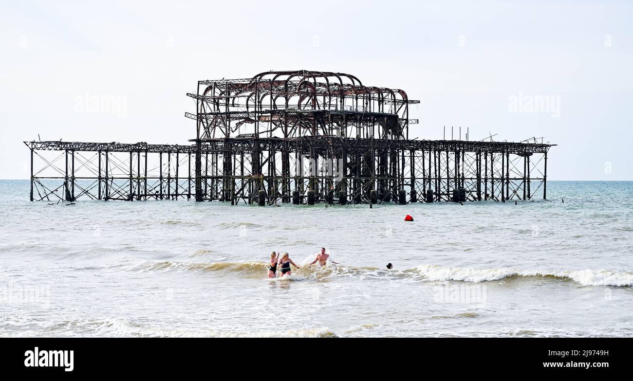 Brighton UK 21st May 2022 - Early morning swimmers enjoy themselves by Brighton's West Pier as warm sunny weather is forecast for this weekend in parts of the UK: Credit Simon Dack / Alamy Live News Stock Photo