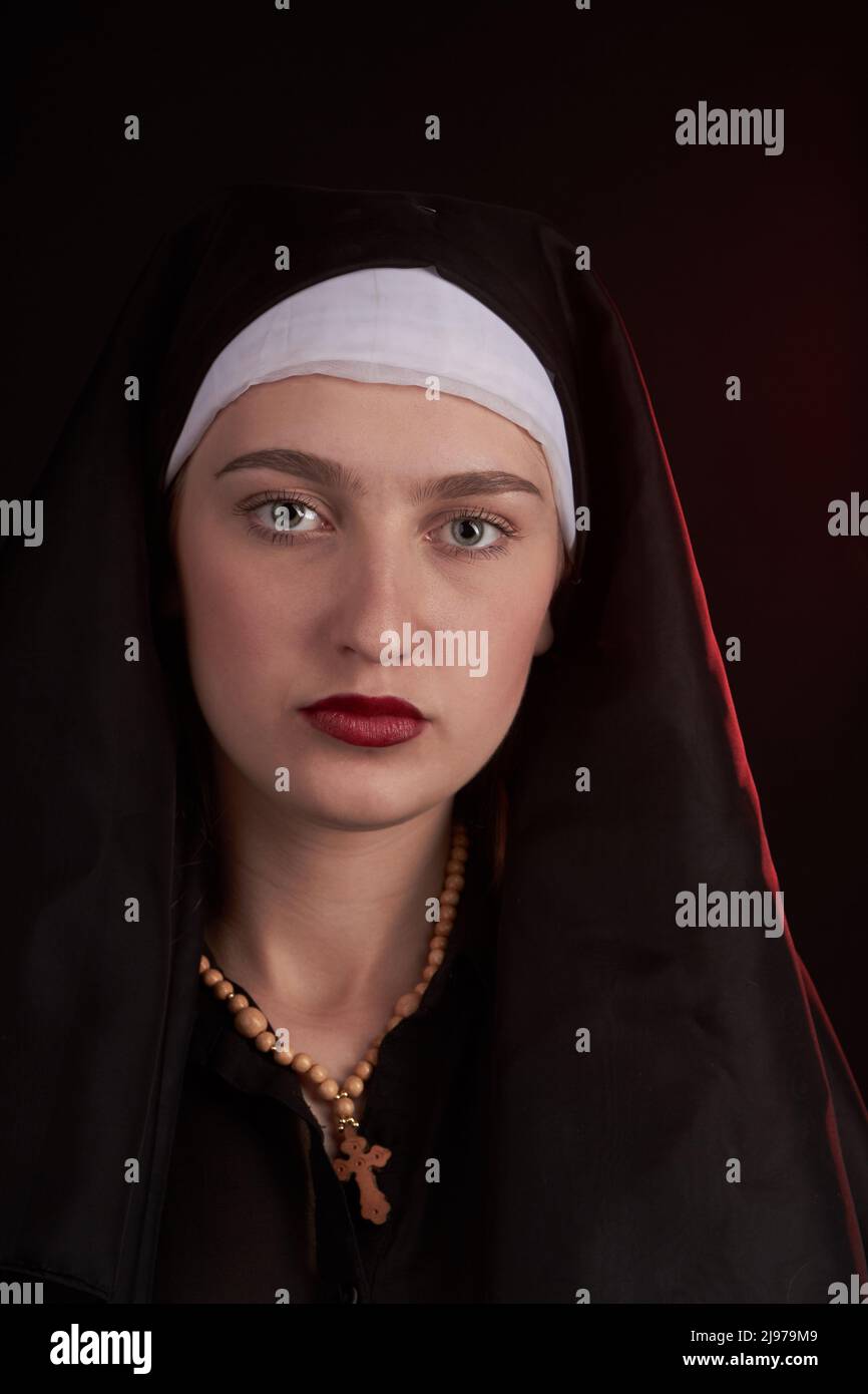 Portrait of a young caucasian christian nun sister girl. Wearint wooden cross. Apathetic indifferent emotion. Stock Photo