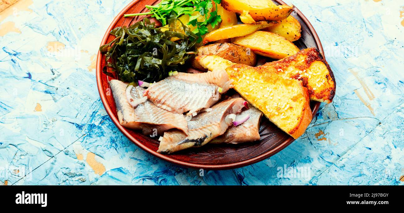 Pieces of salted herring with baked potatoes and toast Stock Photo - Alamy