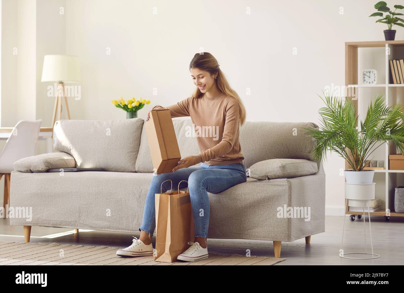 Happy woman who ordered things in online store takes box out of paper delivery bag Stock Photo