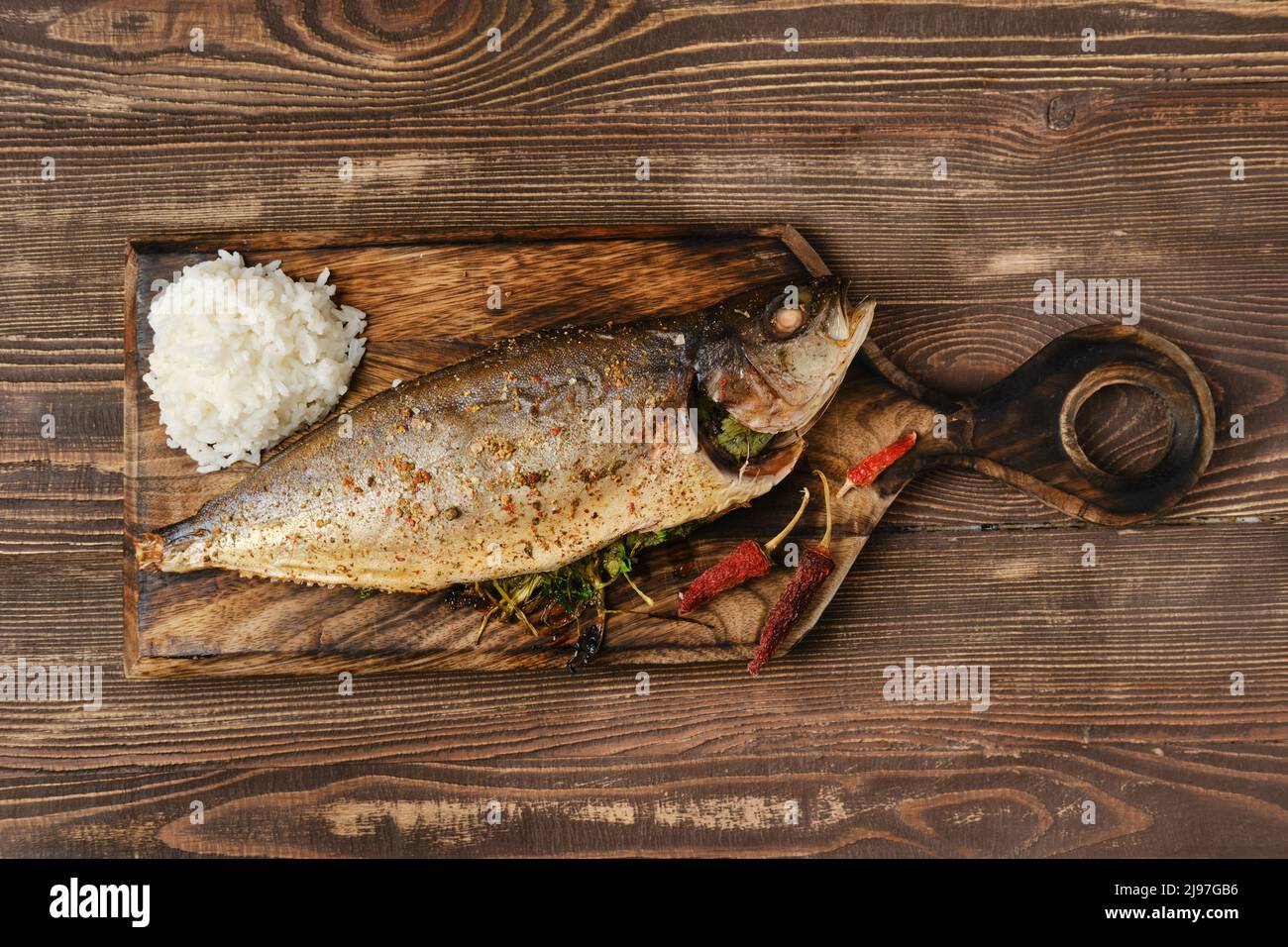 Yellow tailed mackerel with rice baked in oven on wooden cutting board, top view Stock Photo