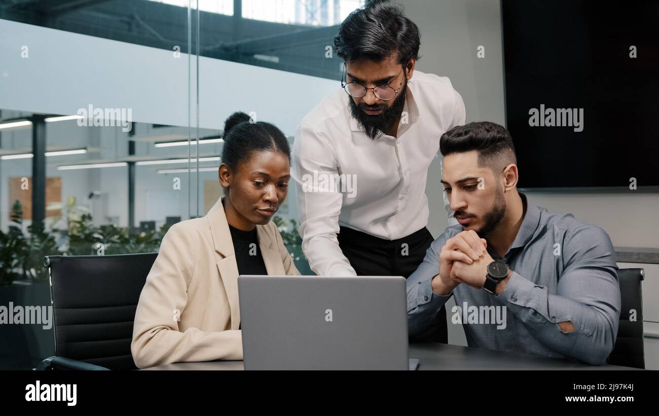 Arab man coach leader boss talking about mistake explain Indian teacher mentor teaching interns managers employees use online app help with software Stock Photo