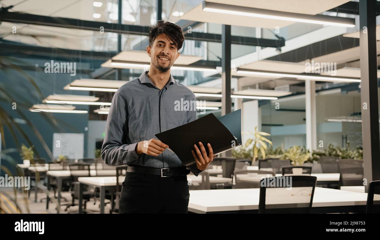 Young arabian confident business man guy stand in modern office hold